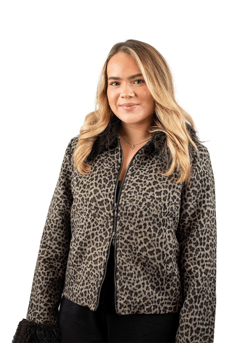 Blonde female student smiling at the camera wearing a leopard print jacket