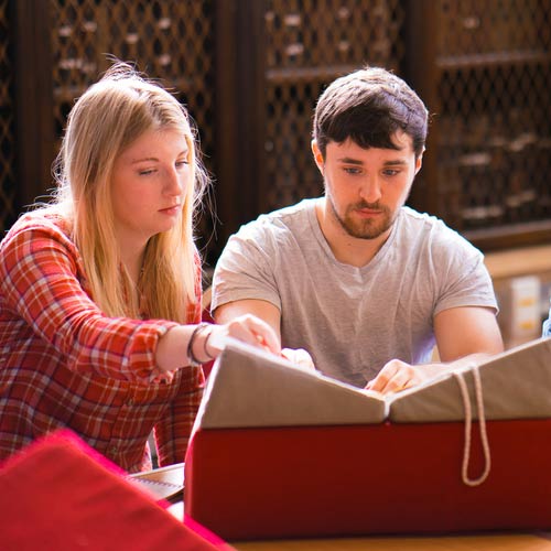 Students work together studying a historic book.