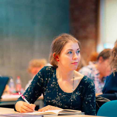 Student taking notes at table in seminar