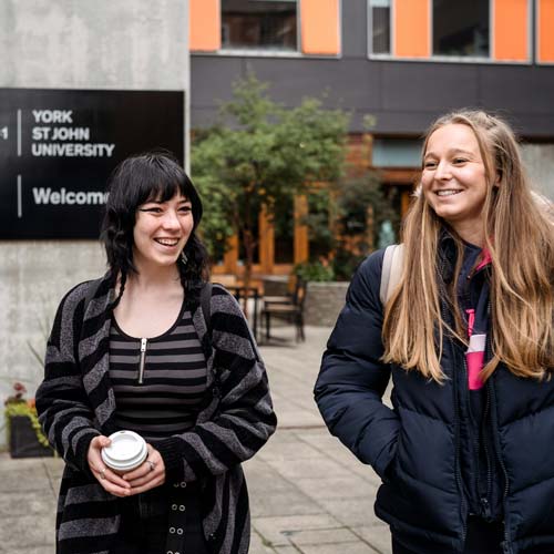 Two students walking in front of entrance to De Grey building
