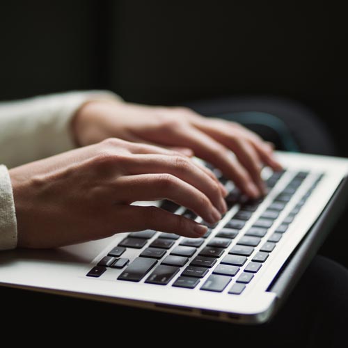 Closing up of hands typing on laptop
