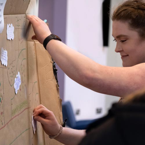 Student adding notes onto map drawn on cardboad
